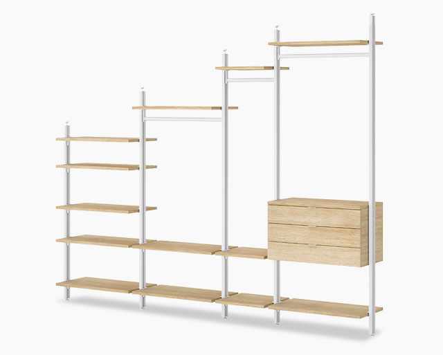 Stufiges Schranksystem für Dachschrägen mit weißen Metallstreben und Kleiderstangen, sowie Holzböden und Schubladenelement in Eicheoptik