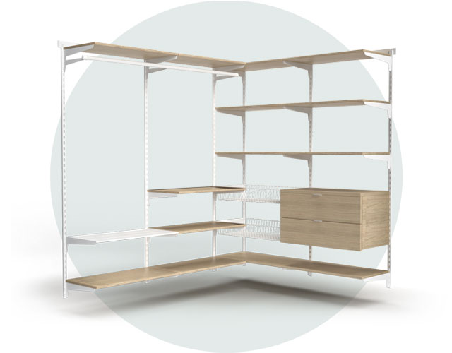 A corner shelving system with white metal strips, wire baskets and clothes rails as well as wooden shelves and drawer units in an oak look