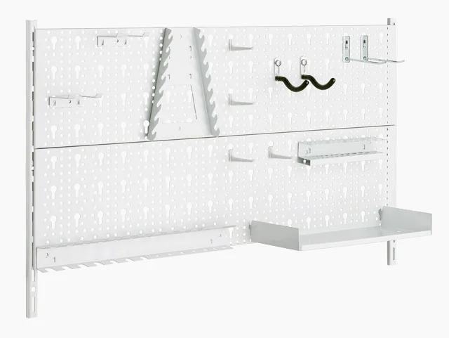 A white tool wall with a perforated surface, equipped with various hooks, holders and shelves